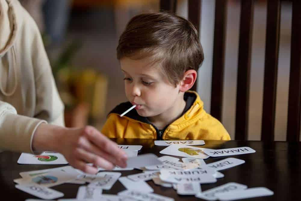 Young Boy At Kitchen Table Doing ABA Therapy Exercises