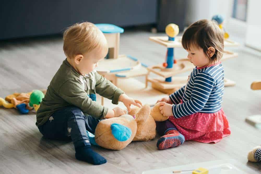 A Boy & Girl Toddler Playing With A Stuffed Bear