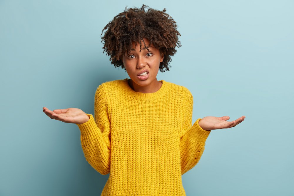 A Woman Standing With Her Arms Up Looking Confused