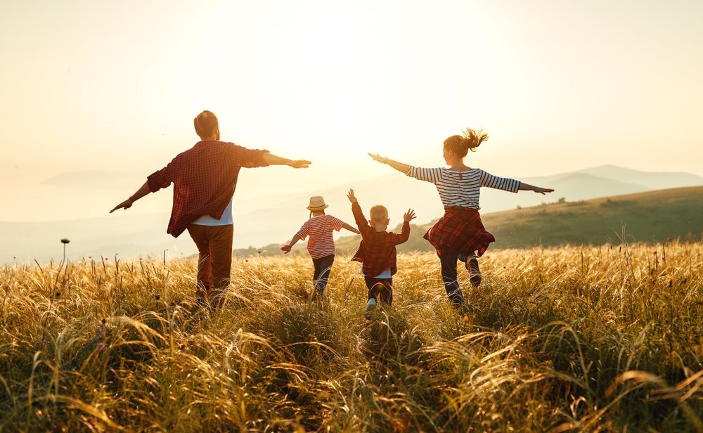 Two Parents With Two Children Running In A Field