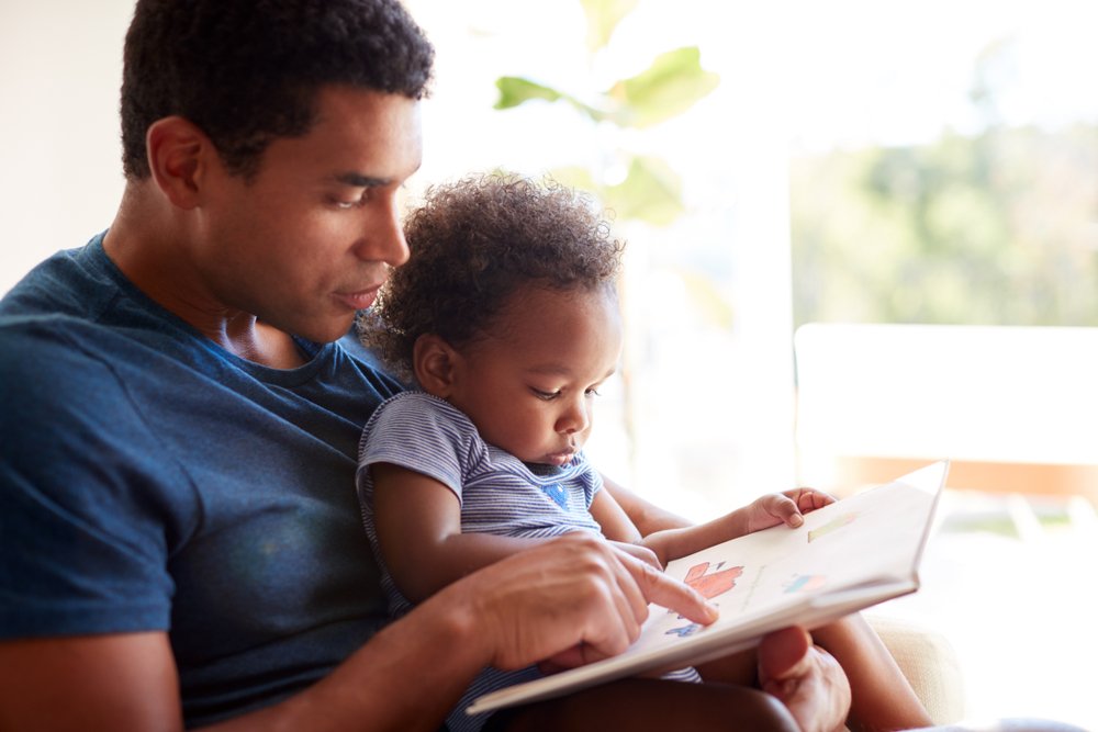 Father Reading A Book To His Daughter
