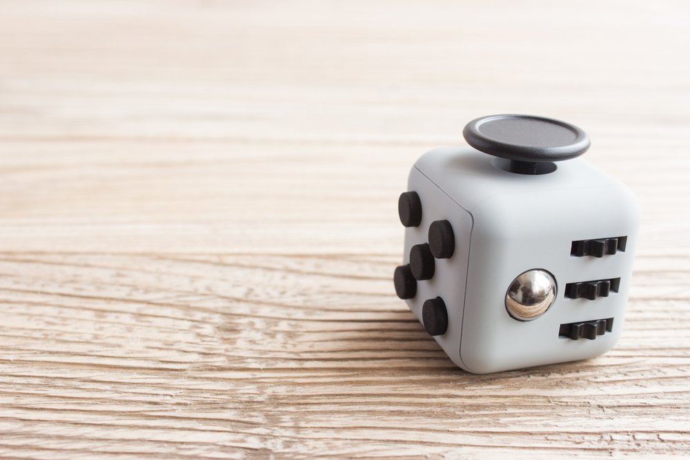 Grey Fidget Cube Sitting On A Wooden Table