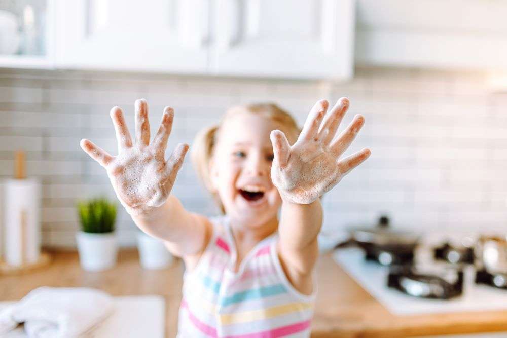 Young Girl Showing Hands Covered In Flour In the Kitchen
