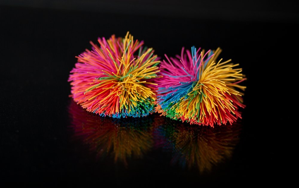 Two Colorful Koosh Balls Or Spaghetti String Balls On A Black Background
