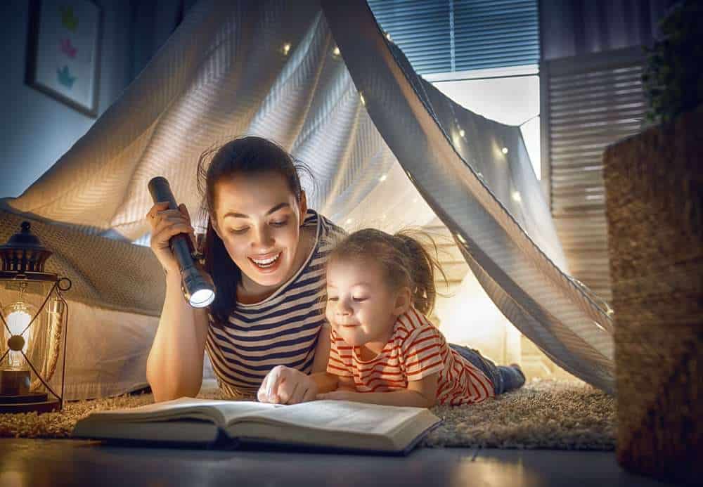 Mother Reading To Her Child With Autism Underneath A Blanket Tent