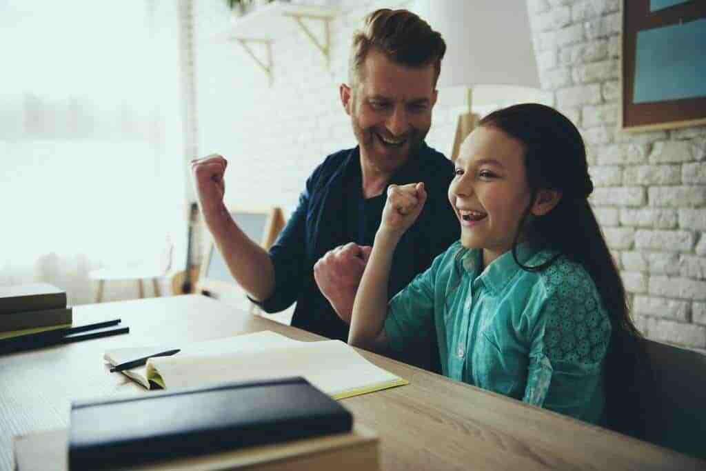 Father Helping His Daughter With Autism Practice Social Skills At Table