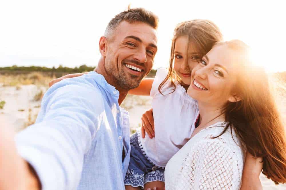 Mother and Father On the Beach Holding Smiling Daughter