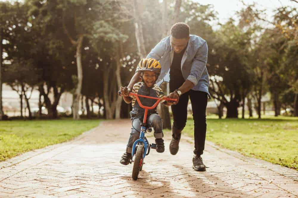 Child having fun riding his bike with his Dad.