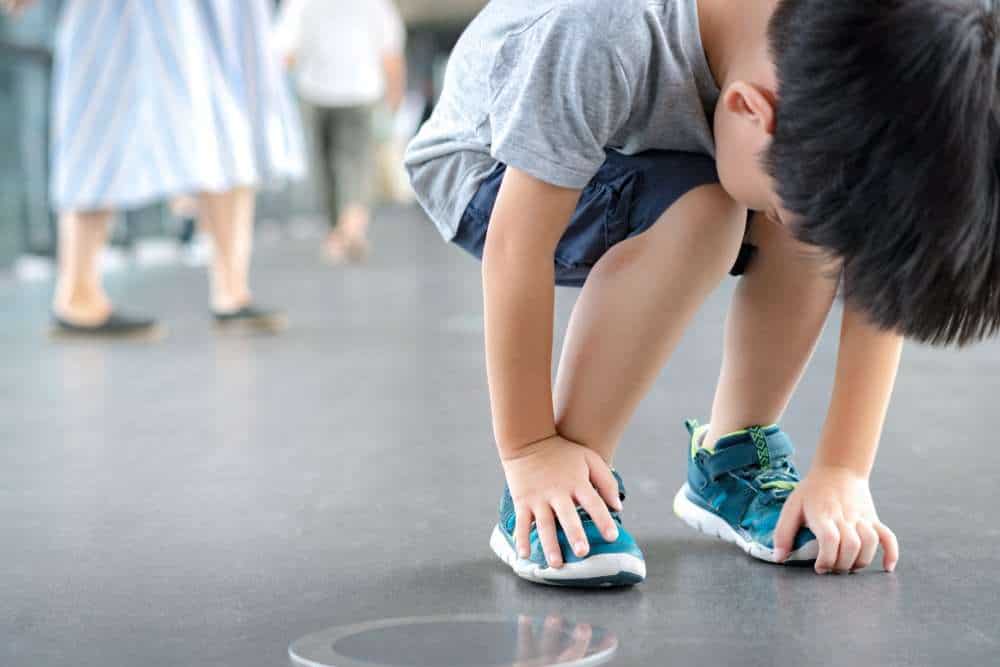 Young Boy With Autism Bending Over To Touch Toes As A Stimming Behavior