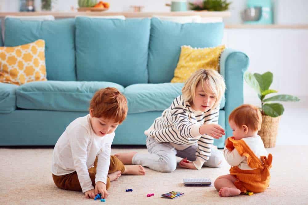 Three Siblings Playing With Toys On The Ground