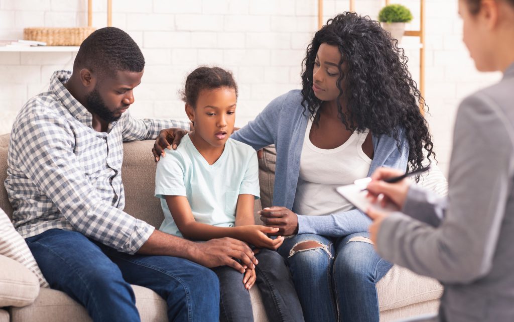 ABA Therapist in NJ Discussing Treatment Plans With A Child And Her Parents On A Couch
