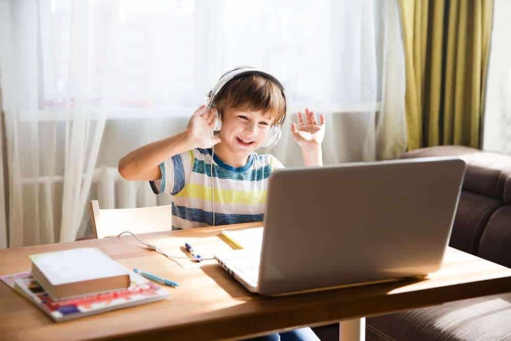 Young Boy With Autism Smiling and Talking To Friends Through A Video Call On A Laptop