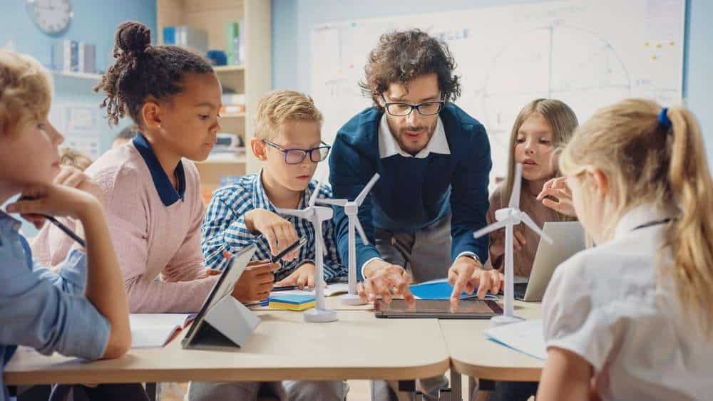 Male Teacher Showing Group Of Kids Science Experiment In Class