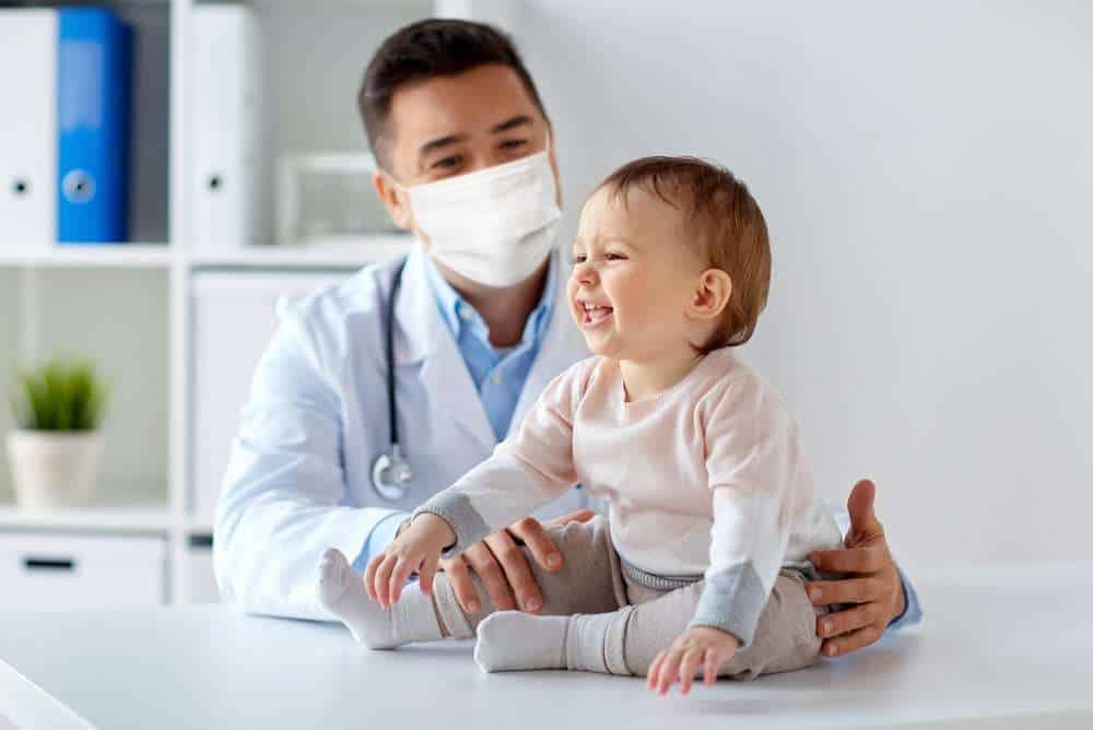 Male Pediatrician Observing Infant For Early Signs of Autism