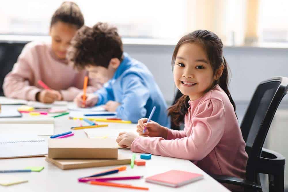 Young Asian Girl Smiling While Working On Schoolwork 