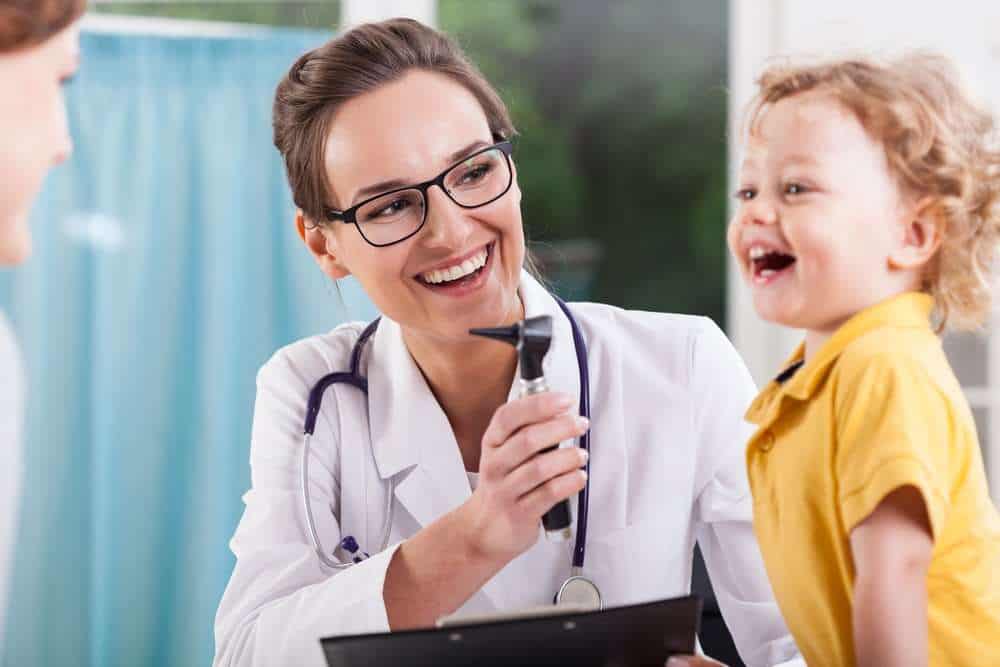 Pediatrician Laughing With A Child With Autism During A Checkup