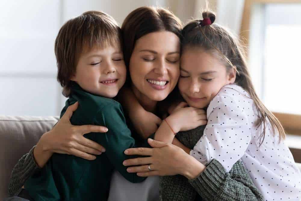 Two Young Kids Hugging Their Mom To Express Gratitude