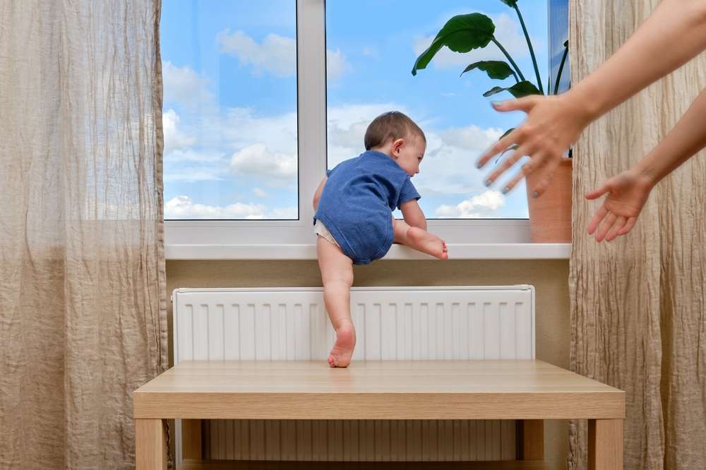 Baby Climbing On Furniture Towards A Window & Parent Trying To Correct Them