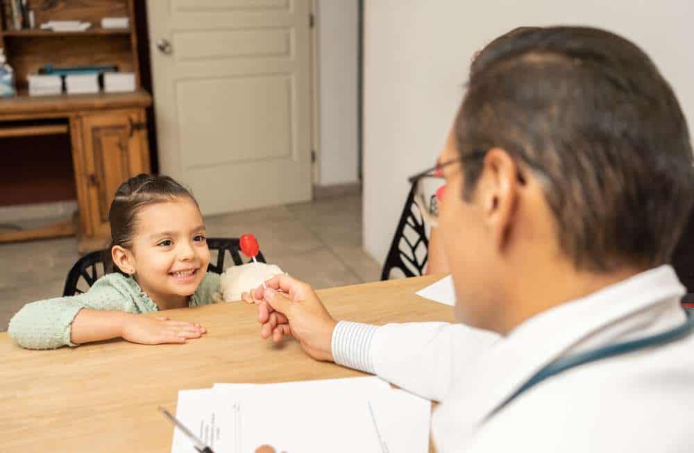 Girl happy when receiving a lollipop from doctor