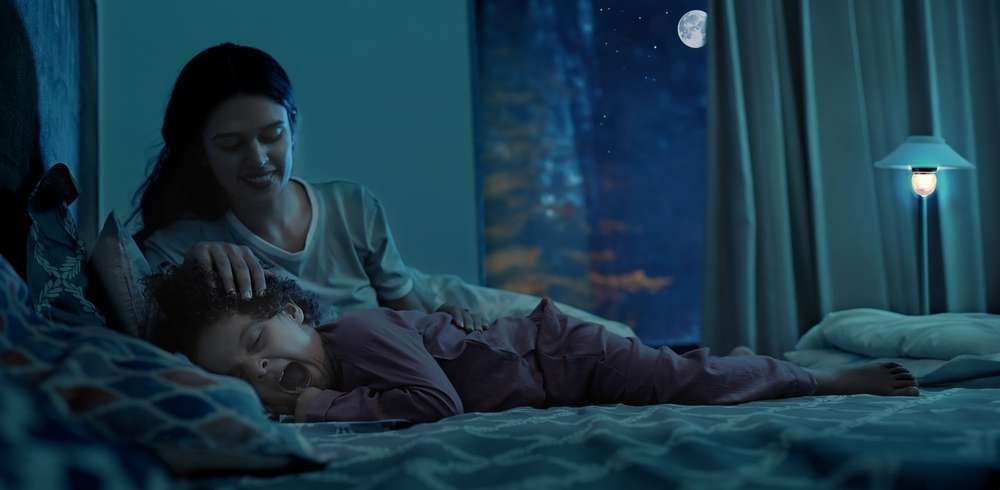 Mother putting her child to sleep