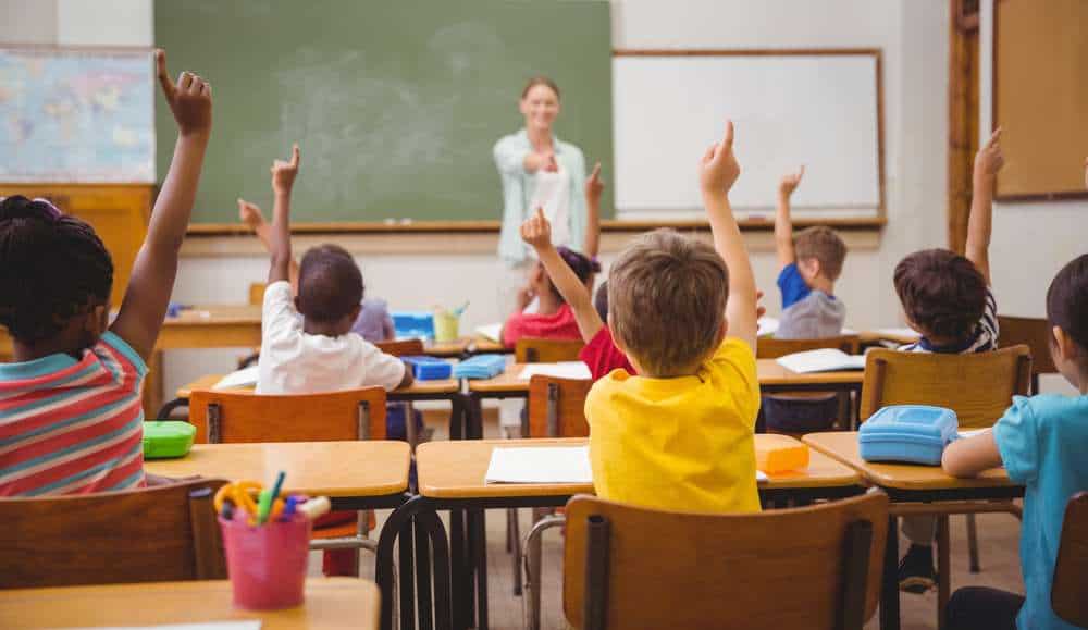 Teacher Calling On Students With Hands Raised During Class