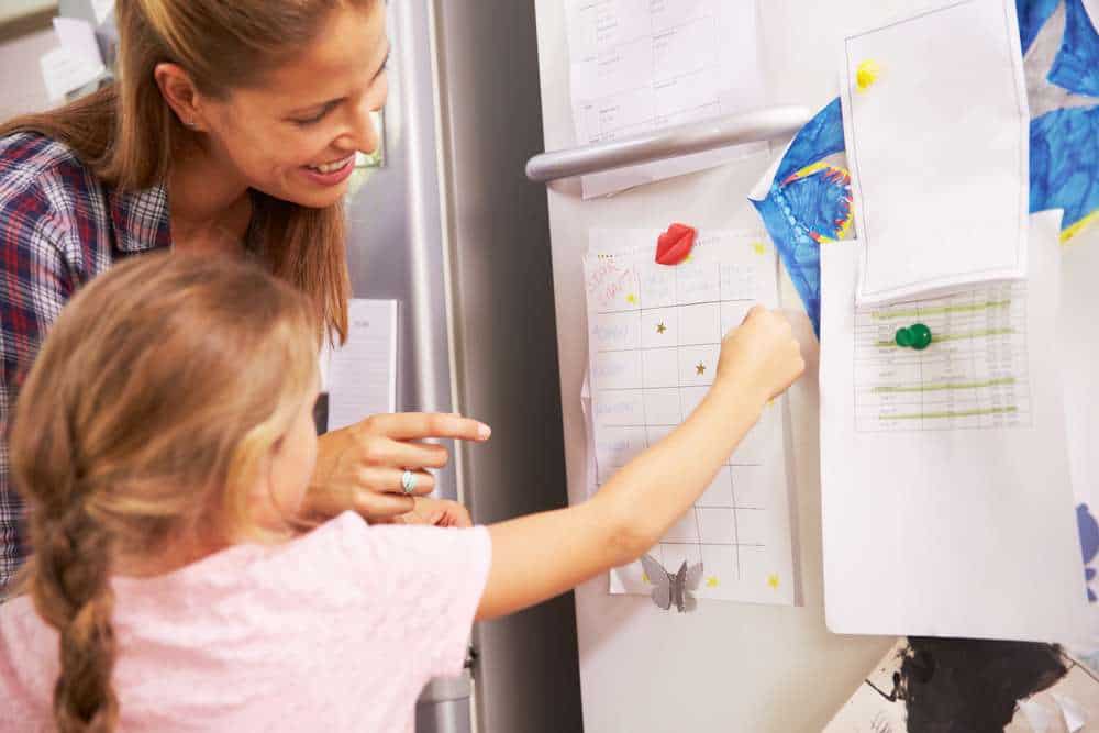 Mother Helping Her Child With A Behavior Chart Pinned