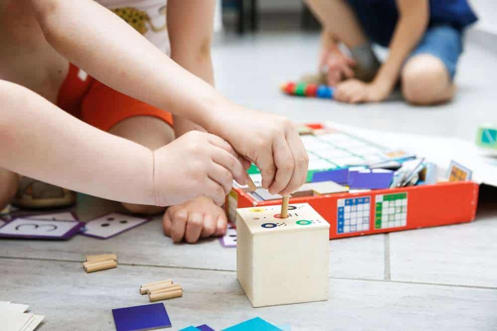Parent Helping Young Child Use A Homemade Development Toy