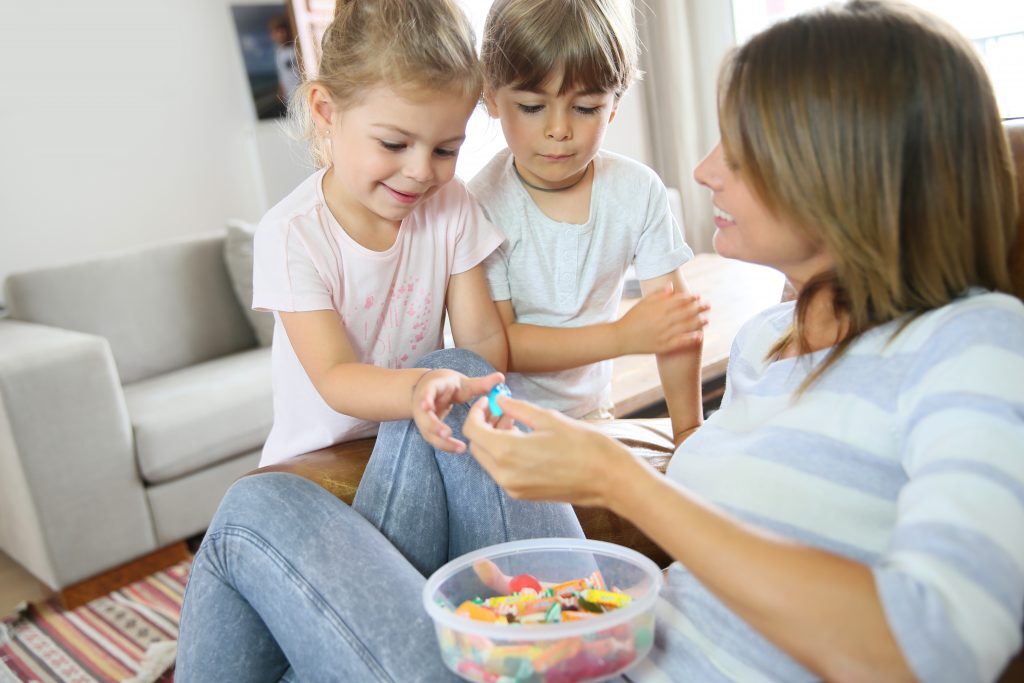 Mother Giving Candy to Son and Daughter to Reinforce Positive Behavior 