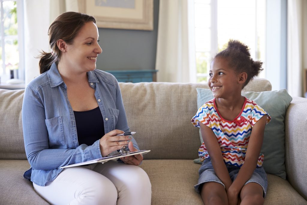 Woman With A Clipboard Discussing ABA therapy in NJ With A Child On A Couch