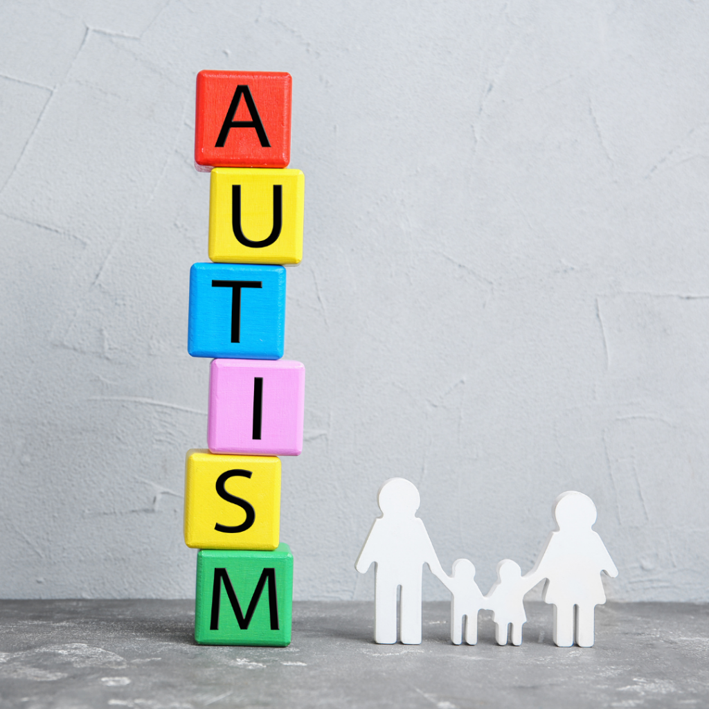 Colorful Blocks Stacked Up To Spell "Autism" Next To Wooden Family Of People