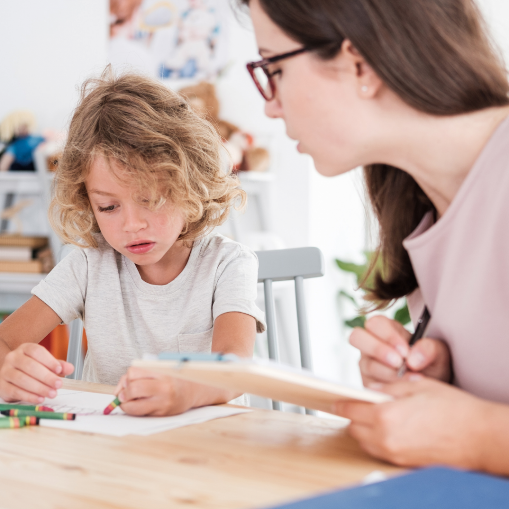 ABA Therapist Reviewing An Exercises With A Child With Autism